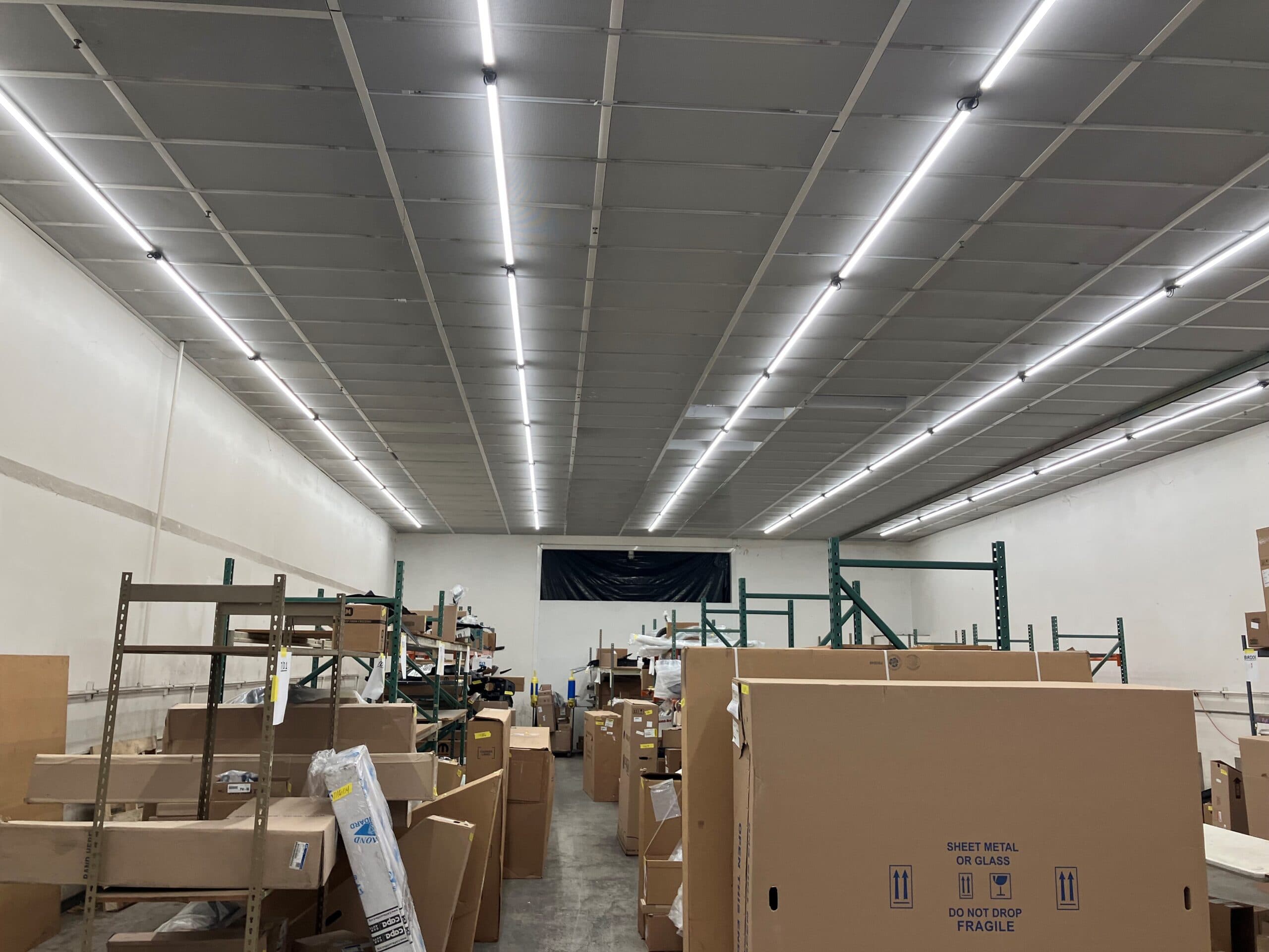 LED strip fixtures installed over pallet racking in a warehouse